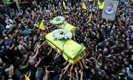 Large crowd passing coffins over their heads.