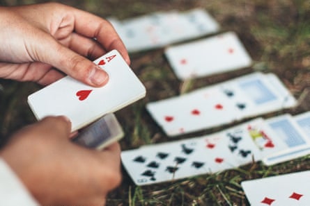 Hands holding an Ace of Hearts card with other cards alligned in front of the person