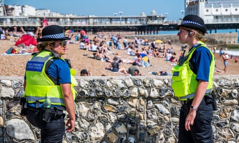 Police community support officers patrol Brighton beach to see if large groups are from the same household.