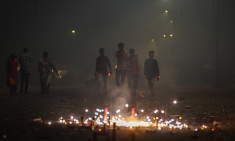 Indian men walk past fireworks amid smog on Diwali 