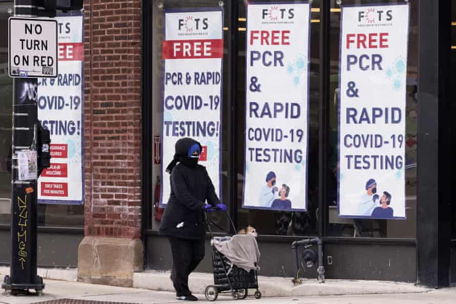 woman walks past testing site with sign saying 'free pcr and rapid covid-19 testing'