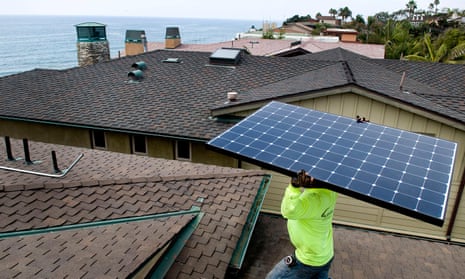 A man installs a solar panel on a home in Encinitas, California.
