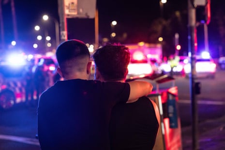 People console each other on Campbell Parade on Bondi Beach following a shooting in the area, NSW, Australia