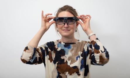 A woman putting on a pair of glasses.