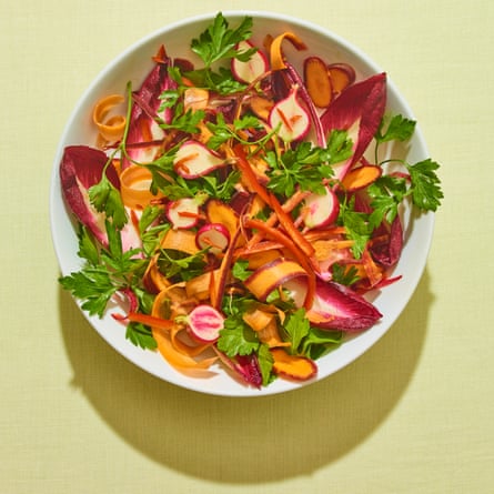 Colourful crudites in white bowl against green background