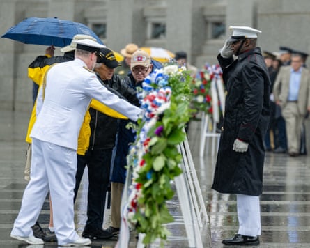 People laying wreaths as a soldiers salutes