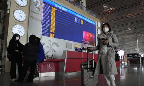 Passengers pass near a flight departure board at a Beijing airport.