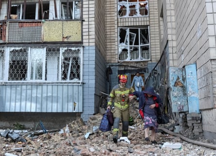 A rescuer evacuates a resident from a bomb-damaged apartment building