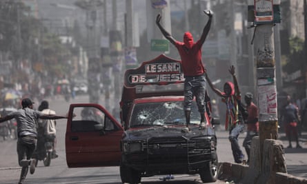 A man with his face covered stands on a vehicle during a protest against prime minister Ariel Henry’s government and insecurity in Port-au-Prince on 1 March 2024.