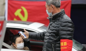A volunteer checks the temperature of passersby at a checkpoint in Hangzhou in east China’s Zhejiang province.
