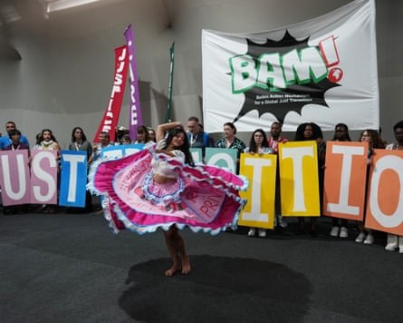 A performer participates in a demonstration near a sign that reads “just transition” a protest for the transition away from fossil fuels at the COP30 UN climate summit.
