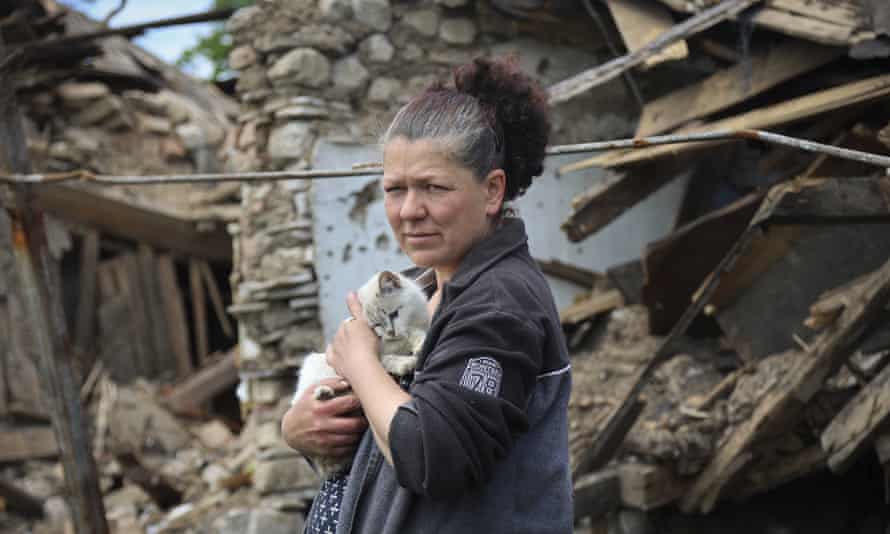 A woman stands next to a destroyed house in Mariupol, eastern Ukraine.