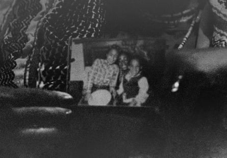 Panther cub Sala Cyril in her home holding a photograph of herself and her sister sitting on the lap of their mother Janet Cyril.
