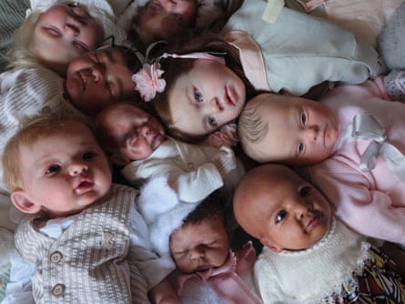A group of reborn dolls, which belong to Margriet Shein, collected together. One, in the foreground, is wearing a cream and white waistcoat.