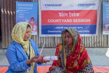 A health worker shows a Bangladeshi women a self-testing kit for cervical cancer while at a health-awareness meeting.