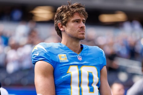 Justin Herbert stands on the sidelines in his blue Chargers jersey, looking to the side