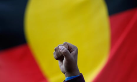A raised fist in front of an Aboriginal flag