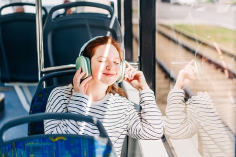 A young person in headphones sitting on a bus