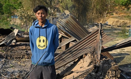 Sanatomba amid the remains of his sister’s house, which was set on fire during ethnic clashes.