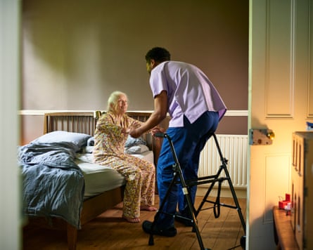 A male care worker helps a smiling elderly woman