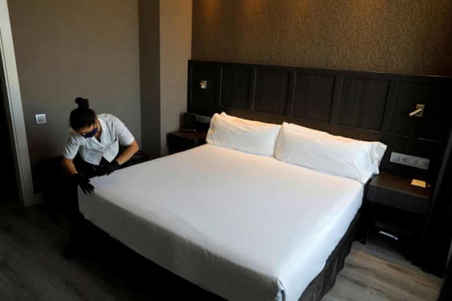 FILE PHOTO: A cleaner wears a protective face mask and gloves while she makes up a suite room 