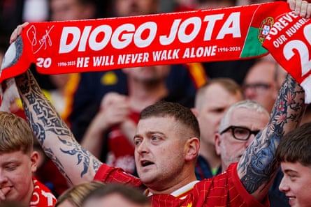 A Liverpool fan holds up a scarf in trubute for Diogo Jota.
