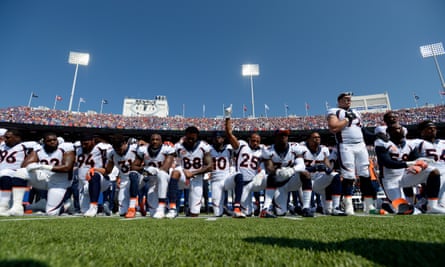 Denver Broncos team take a knee during the national anthem.