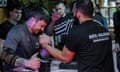 Two men arm wrestling with strained faces and elbows planted on black blocks