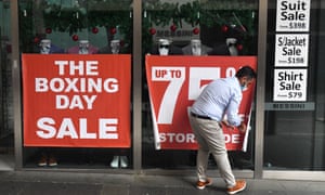 A shop attendant adjusts a sign outside a store on Pitt Street in Sydney