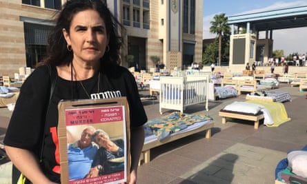 Yael Moshe holds a placard of her murdered father, David, and kidnapped mother, Adina, at a ceremony in Jerusalem.