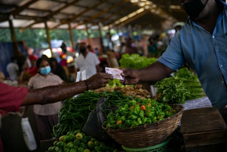 A man pays for vegetables at a market in Colombo.