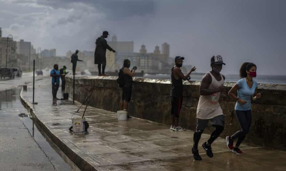 Joggers and fishermen in the rain on the Malecon, Havana famous sea wall.