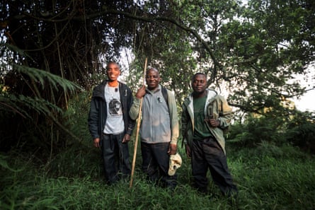 Three man stand in front of a tree in a forest