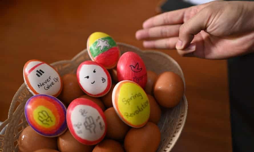 A person makes the three-finger salute beside a bowl of eggs decorated with messages in support of protesters in Yangon