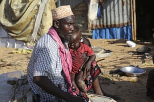 Hassan Mohamed Yusuf, a 45-year-old father, sits with his family at their make shift shelter Dayniile camp, in Mogadishu, Somalia.