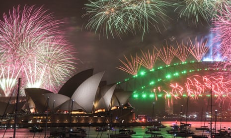 the sydney opera house and sydney harbour bridge underneath coloured fireworks on new year's eve