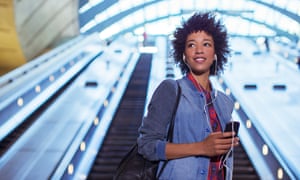 woman listening to earbuds on escalator