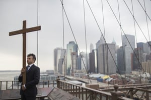 Framed by lower Manhattan, Vladimir Kuzmin carries the cross during a procession on Brooklyn bridge, New York.