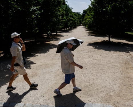 A man uses an umbrella to cover from the sun at El Retiro park in Madrid, Spain.