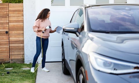 Woman holding charging cable while standing by electric car