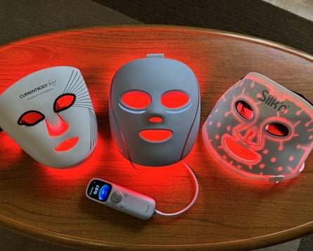 Three masks on a table with remote and red light behind them.