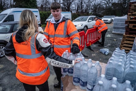 Workers in hi-vis hand out bottles of water