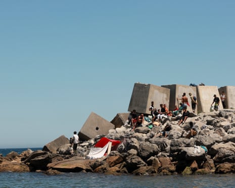 Migrants wait at a breakwater on a beach in Ceuta, Spain.