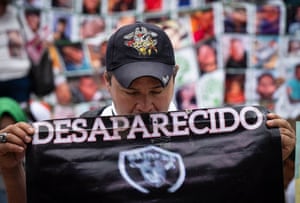 A man holds up a sign reading 'desaparecido' (disappeared)