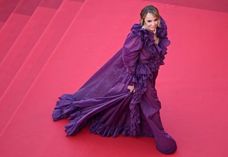 she wears a long, flowing frilled purple gown with long, puffed sleeves.