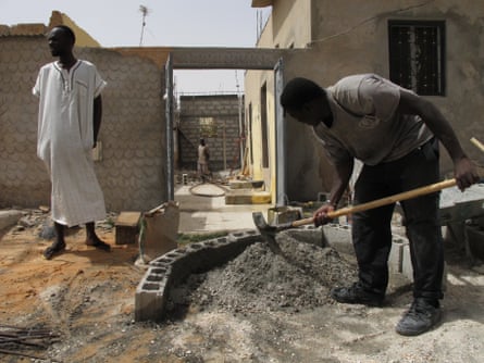 Vieux Fall, left, stands in the family compound in Nouakchott, Mauritania, as builders work