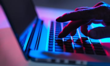 Hand on laptop keyboard in blue and red lighting