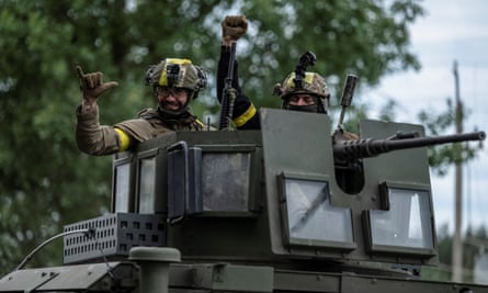 Ukrainian service members gesture as they ride an armoured vehicle near the Ukraine-Russia border in the town of Vovchansk.