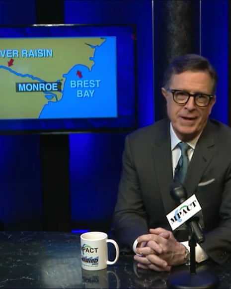 A middle-aged man at a public access TV set with a map behind him on a screen.