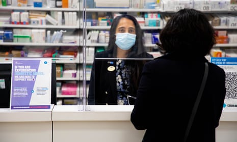 A woman speaks to a shop assistant in a Boots pharmacy